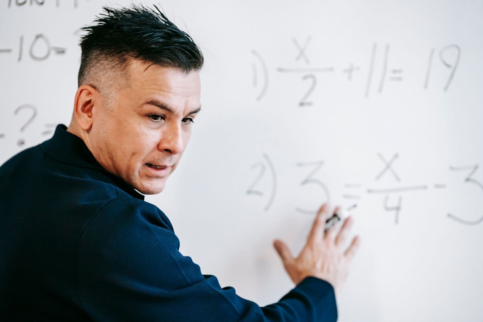 Tutor explaining a maths problem on a whiteboard during a lesson